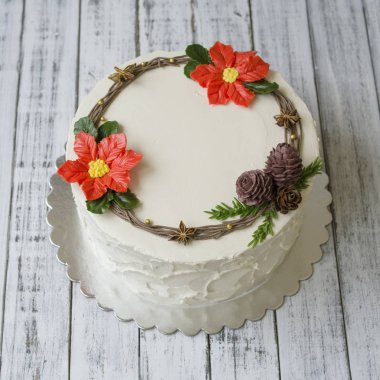 Beyaz yeni yıl veya Noel kek krem Atatürk çiçeği çiçek, çam kozalakları ve bir beyaz tahta masada çam çırpı ile dekore edilmiştir. Kışın doğanlar için bir Doğum günü pastası. Kopya alanı, seçici odak