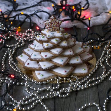 Antika ahşap zemin üzerine ev yapımı pişmiş Noel kurabiye ağacı. Gümüş boncuk ve yeni yıl atmosfer için renkli ışıklar. İle krema şeker kar gibi. Selfmade xmas hediyesi. Seçici odak
