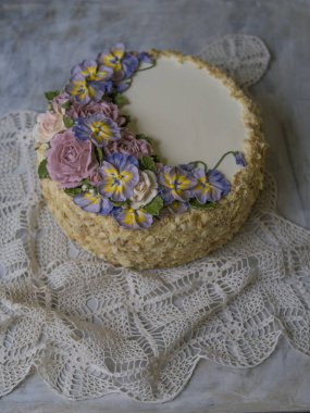 Napolyon pasta vanilya krema ile dekore edilmiş buttercream çiçek - gül ve hercai menekşe. Vintage tarzı. Gri arka plan, dantel peçete. Uzay kopyalayın, yakın çekim
