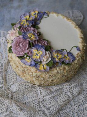 Napolyon pasta vanilya krema ile dekore edilmiş buttercream çiçek - gül ve hercai menekşe. Vintage tarzı. Gri arka plan, dantel peçete. Uzay kopyalayın, yakın çekim