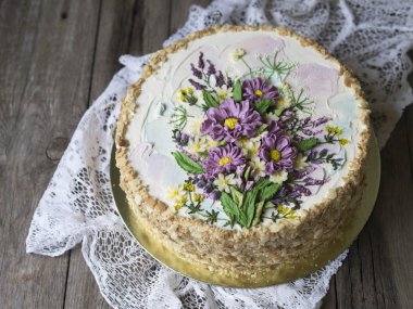 Napolyon pasta vanilya krema ile buttercream çiçek - yaz kır çiçekleri ile süslenmiş. Vintage tarzı. Ahşap arka plan, dantel peçete. Uzay kopyalayın, yakın çekim