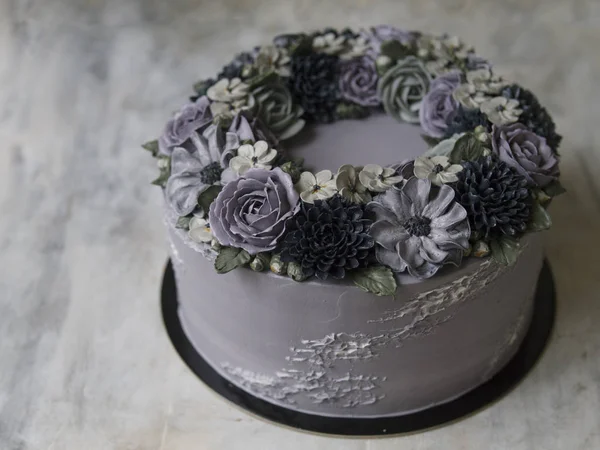 Gray cream cake decorated with dark buttercream flowers on rustic background. Halloween cake. Black cake. Close up, copy space