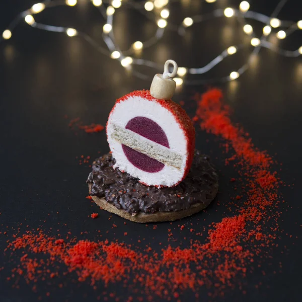Mousse cake made in the form of New Year\'s decoration - tree toy, ball, with berry jelly, biscuit in chocolate icing. Delicious unusual dessert for the Christmas table. Copy space, selective focus
