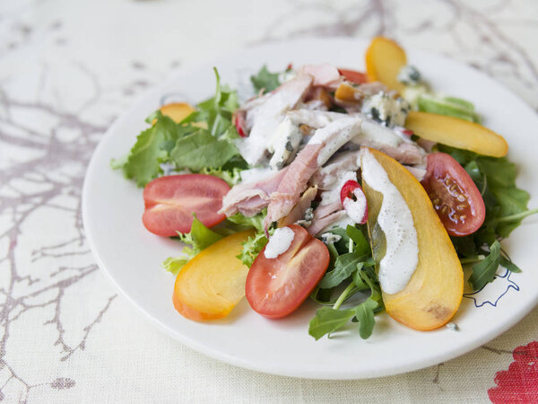 Салат с хурмой, курицей, помидорами черри, сыром Камамбер и соусом из голубого сыра. Праздничное блюдо. Рождественский ужин. Селективный фокус, крупный план, пространство для копирования
