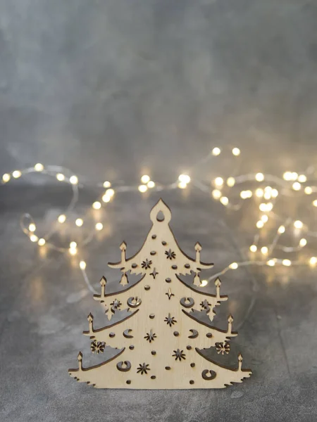 Stilvoller handgemachter Weihnachtsbaum aus Holz auf grauem Hintergrund mit leuchtenden Lichtern. Overhead von Weihnachten Neujahr Urlaub Hintergrund. selektiver Fokus, Platz für Text — Stockfoto