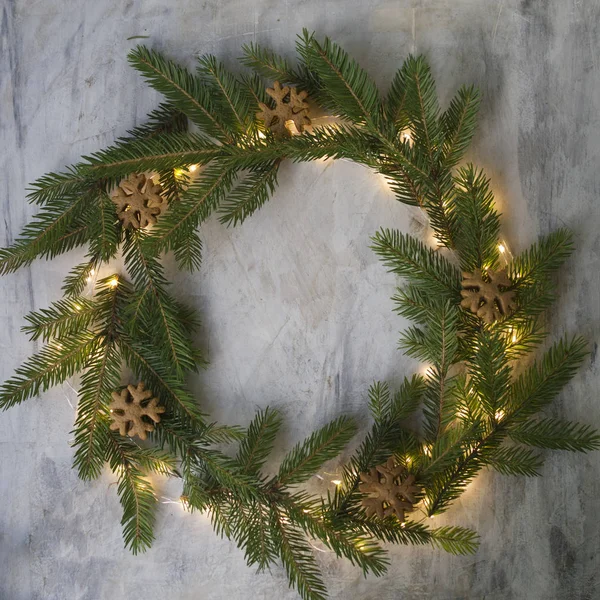Christmas wreath made of fir branches, cookies and glowing lights on gray background. New Year background. Christmas card. Flat lay, place for text — Stock Photo, Image