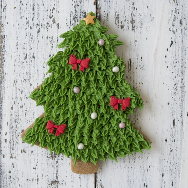 Eine grüne Glasur weihnachtlicher Lebkuchen in Form eines Weihnachtsbaums auf einem weißen Holztisch. Nahaufnahme, selektiver Fokus, Kopierraum, flache Lage, Draufsicht — Stockfoto