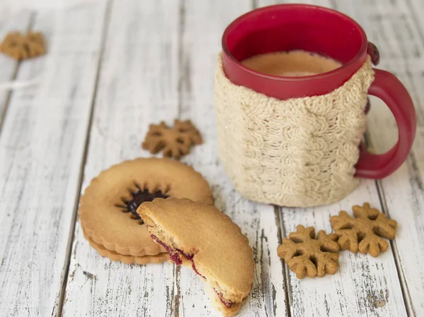 Winter morning, cup of coffee with knitted cup holders, gingerbread and vanilla cookies on a white wooden background.Cozy winter breakfast.Ideal for winter couple in love. Copy space, selective focus — Stock Photo, Image