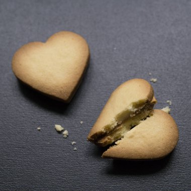 Kalp, bir tanesi şeklinde iki aşçı siyah arka plan üzerine bozuldu. Kırık kalp şeklinde çerez ayrılık ve ilişki, karşılıksız aşk sonu bir kavram olarak. Sevgililer günü kartı. Üstten görünüm