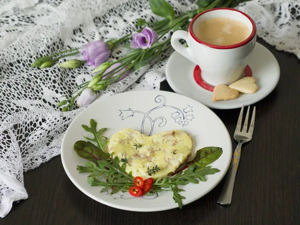 Omelet with tuna and green salad, a cup of coffee with cookies in the shape of a heart against the background of delicate flowers. Valentine\'s day or Mother\'s Day breakfast concept. Selective focus