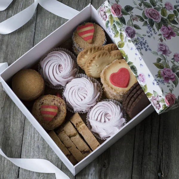Box of sweets: cookies, marshmallow, meringue in a box on the table, cookies in the shape of a heart. a romantic gift for Valentine\'s day or Women\'s Day. Festive Card with Assorted Cookies, top view