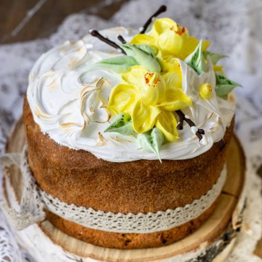 Paskalya kek kulich. Geleneksel Paskalya tatlı ekmek beze, dantel kumaş ahşap zemin üzerine sarı nergis dekore edilmiştir. Kopya alanı, seçici odak, yakın çekim. Dilekler kartı.