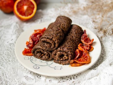 İnce çikolatalı krep içine bir tüp kan portakal soslu beyaz bir plaka üzerinde rulo. Krep, yığını Rus blin, Maslenitsa. Lezzetli kahvaltı. Seçici odak. yakın çekim, alanı Kopyala