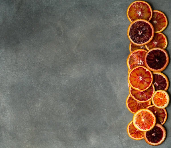 Blood juicy Sicilian orange slices on gray background. Sliced blood orange texture. Citrus background. Copy space, selective focus, top view. Minimalism style