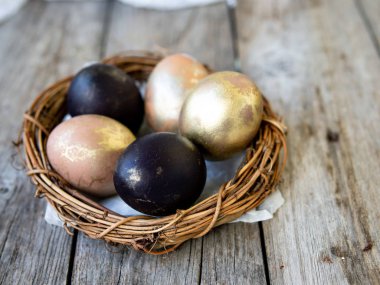 Bir yuva eski bir ahşap zemin üzerinde altın ve siyah yumurtalar. Kopya alanı, seçici odak, yakın çekim. Yumurta Paskalya için. Kartı.