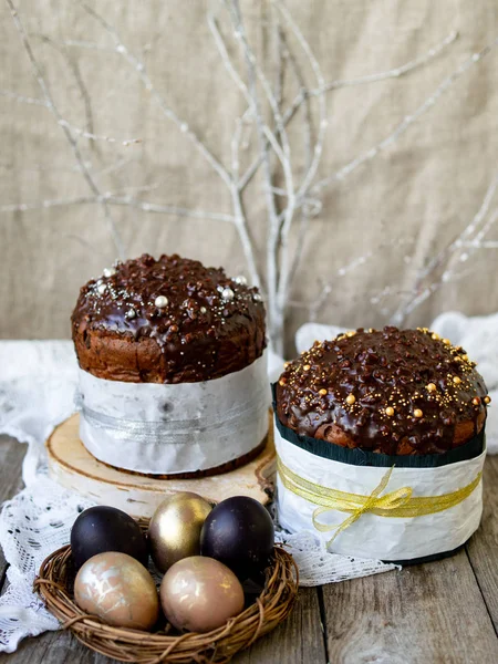 Amazing Chocolate Easter Cake with chocolate drops and dry cherries on an old wooden background with black and golden eggs. Easter concept. Selective focus, close up, copy space.