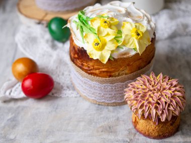 Paskalya pastası Kulich. Geleneksel Paskalya tatlı ekmek süslenmiş Meringue, dantel kumaş ve renkli yumurta ile ahşap gri arka plan üzerinde sarı nergis. Kopya alanı, seçici odak. mevsim tebrik kartı.