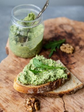 Ceviz ile Arugula pesto. Ahşap bir plaka üzerinde pesto ile sandviç. Sağlıklı kahvaltı. Vejetaryen yemek. Seçici odak, kopya alanı, kapatmak, rustik.