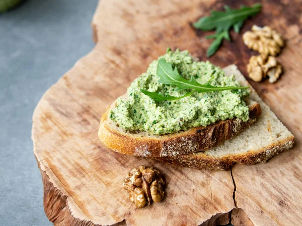 Ceviz ile Arugula pesto. Ahşap bir plaka üzerinde pesto ile sandviç. Sağlıklı kahvaltı. Vejetaryen yemek. Seçici odak, kopya alanı, kapatmak, rustik.
