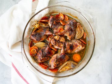 Sebze ile Lezzetli kızarmış Bıldırcınlar - sarımsak, havuç, soğan, hafif bir arka plan ile cam formda pişmiş. Diyet, gurme öğle yemeği. Yakın çekim, seçici odak.