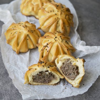 İlginçtir beyaz kağıt ile gri masada taze et mini pasta şeklinde. Kıyma ve baharat ile etli börekler samosas. Bir parça turta. Menü, restoran, tarif konsepti. Yakın çekim, seçici odak.