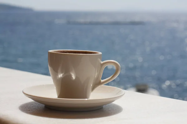 White cup with coffee on the background of the sea. Sunny day, vacation at sea. Enjoyment moment. Enjoying a cup of coffee by the sea. — Stock Photo, Image