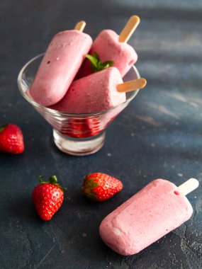 Koyu arkaplanda cam bir kasede yoğurdun üzerinde çilekli dondurma. Diyet, sağlıklı beslenme. Yaklaş, kopyalama alanı. Sıcak hava ve yaz için güzel yemekler..