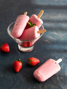 Koyu arkaplanda cam bir kasede yoğurdun üzerinde çilekli dondurma. Diyet, sağlıklı beslenme. Yaklaş, kopyalama alanı. Sıcak hava ve yaz için güzel yemekler..
