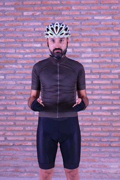 Spor giyim sektöründe kendinden emin genç bir bisikletçi kameraya kararlı bir şekilde bakıyor.