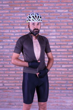 Genç bisikletçi kameraya bakarak giyiniyor.