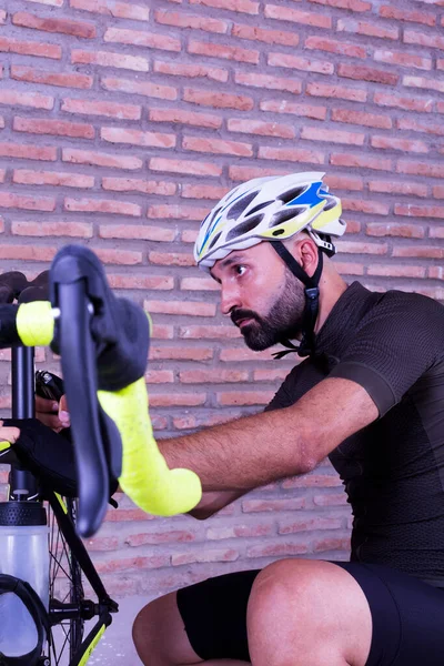 Bisikletçi bisikletini tuğla duvarın yanına ayarlıyor.