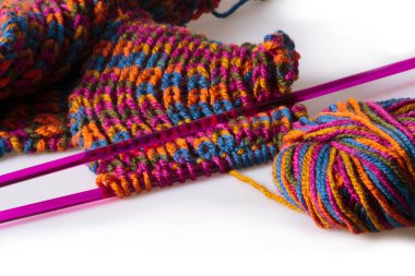 Tamamlanmamış el yapımı yün eşarp, örgü iğneleri ve bir tüy yumağı