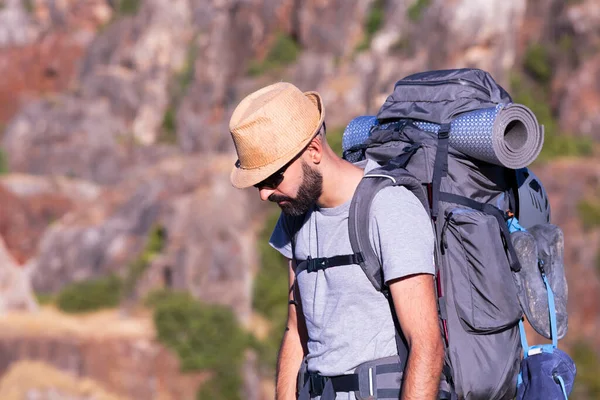 Trekker masculino hispano con gafas de sol y una mochila llena mirando hacia abajo — Foto de Stock