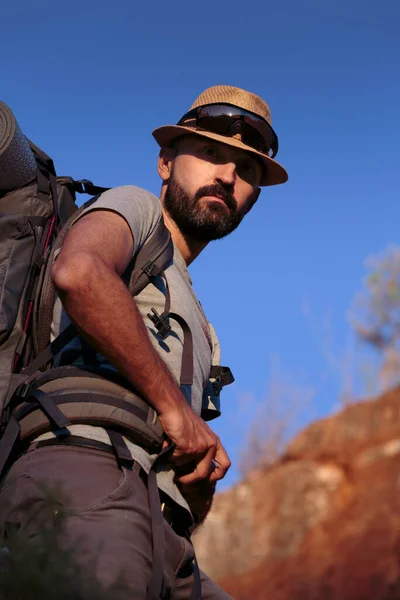 Genç İspanyol erkek yürüyüşçü, spor kıyafetleri ve ağır sırt çantasıyla, İberya 'da yaz aylarında yapılan bir gezi sırasında daha yüksek bir yerden kameraya bakıyor..