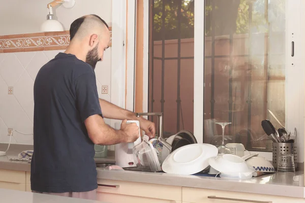 Genç İspanyol erkek kazanı suyla dolduruyor.