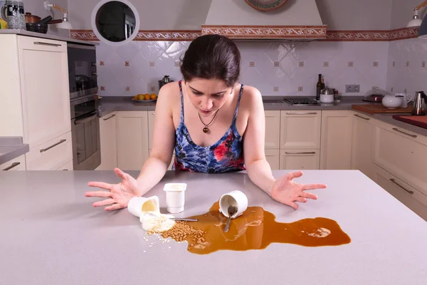 Pretty young woman looking perplexed at a mess on the counter