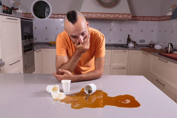 Suçluluk duygusuyla tezgahtaki pisliğe bakan genç adam.