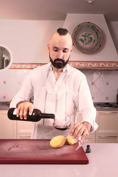 Kafkasyalı erkek şef kendine kırmızı şarap servis ediyor.