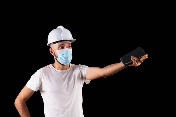 Young hispanic male construction worker with mask estimating a measurement — Stock Photo, Image