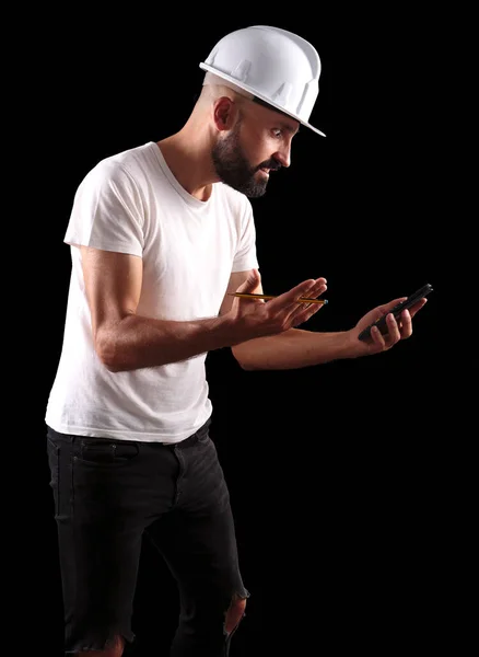 Hüsrana uğramış genç erkek inşaat işçisi hesap makinesine bakıyor.