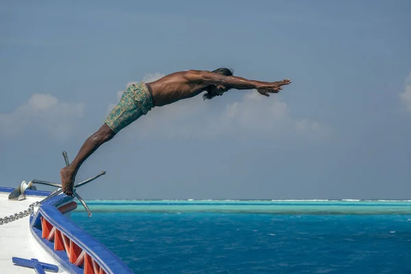Мальдивский мужчина ныряющий с лодки в голубом океане — стоковое фото
