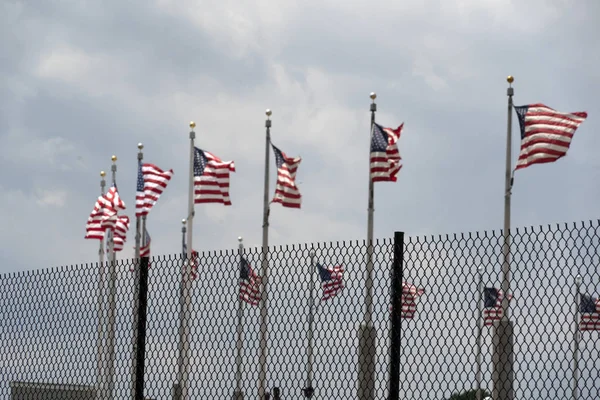 Acenando bandeiras dos EUA atrás da grade de vedação — Fotografia de Stock