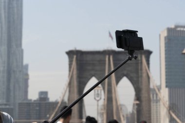 Güneşli bir günde Brooklyn köprüsünde akıllı telefon ve tripod ile selfie