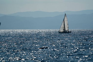 Derin mavi deniz ve gökyüzü arka planında küçük yelkenli