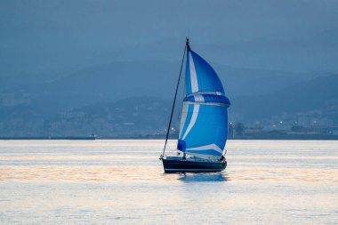 Günbatımında küçük yelkenli arka planda