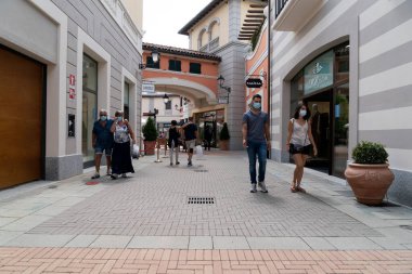SERRAVALLE SİVİYA, İTALYA - 12 Temmuz 2020 - Tasarımcı satış sezonunun başında pek çok insan kapalı gişe maskesini takarak moda ürünleri satın alıyor