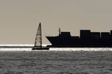 Büyük gemi ve küçük yelkenli gemi deniz ufku çizgisi manzarasında