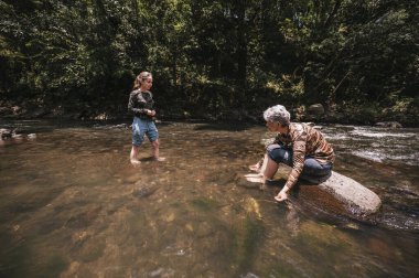 Anne ve kızı sıcak bir yaz gününde nehirde eğleniyor ve serinliyor..