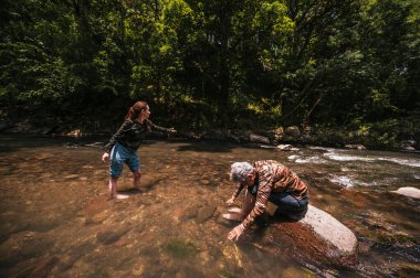 Anne ve kızı sıcak bir yaz gününde nehirde eğleniyor ve serinliyor..
