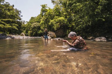 Anne ve kızı sıcak bir yaz gününde nehirde eğleniyor ve serinliyor..